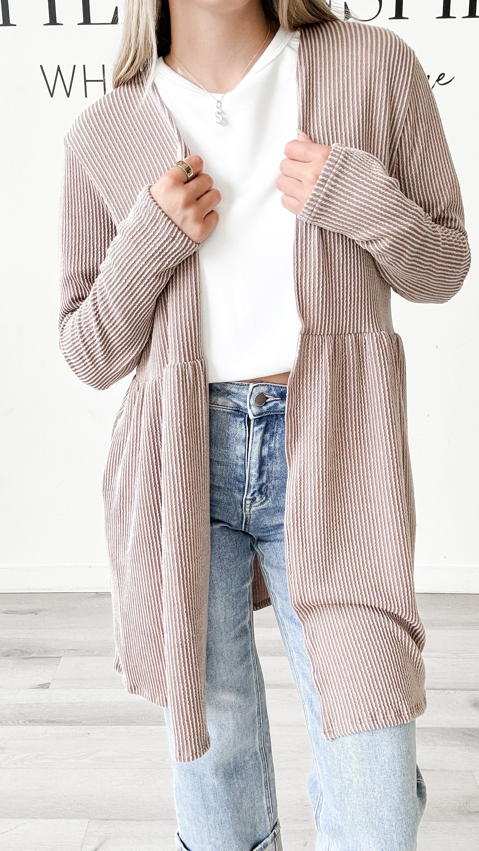 Person wearing a striped cardigan over a white shirt and jeans.